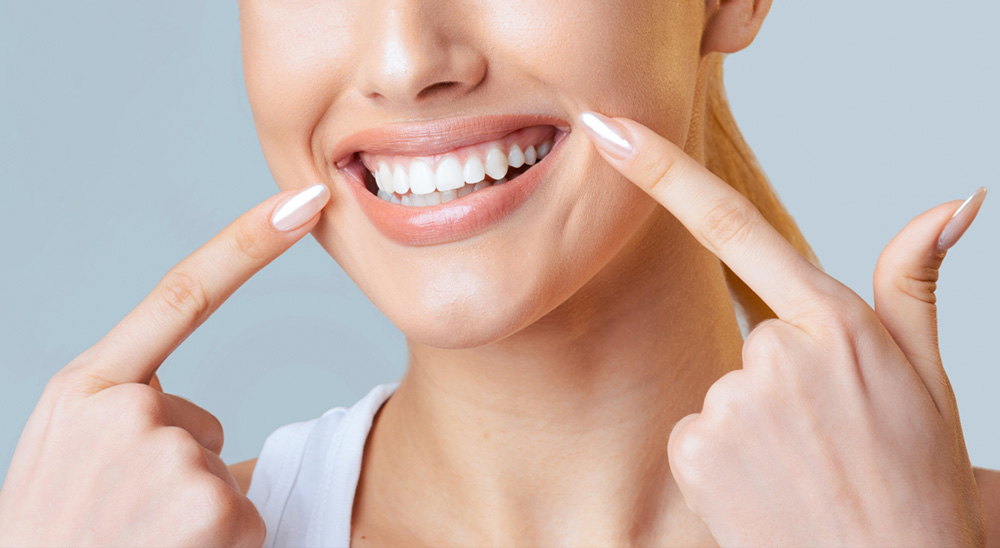 close up of a woman face her fingers are resting on her cheeks and she is smiling